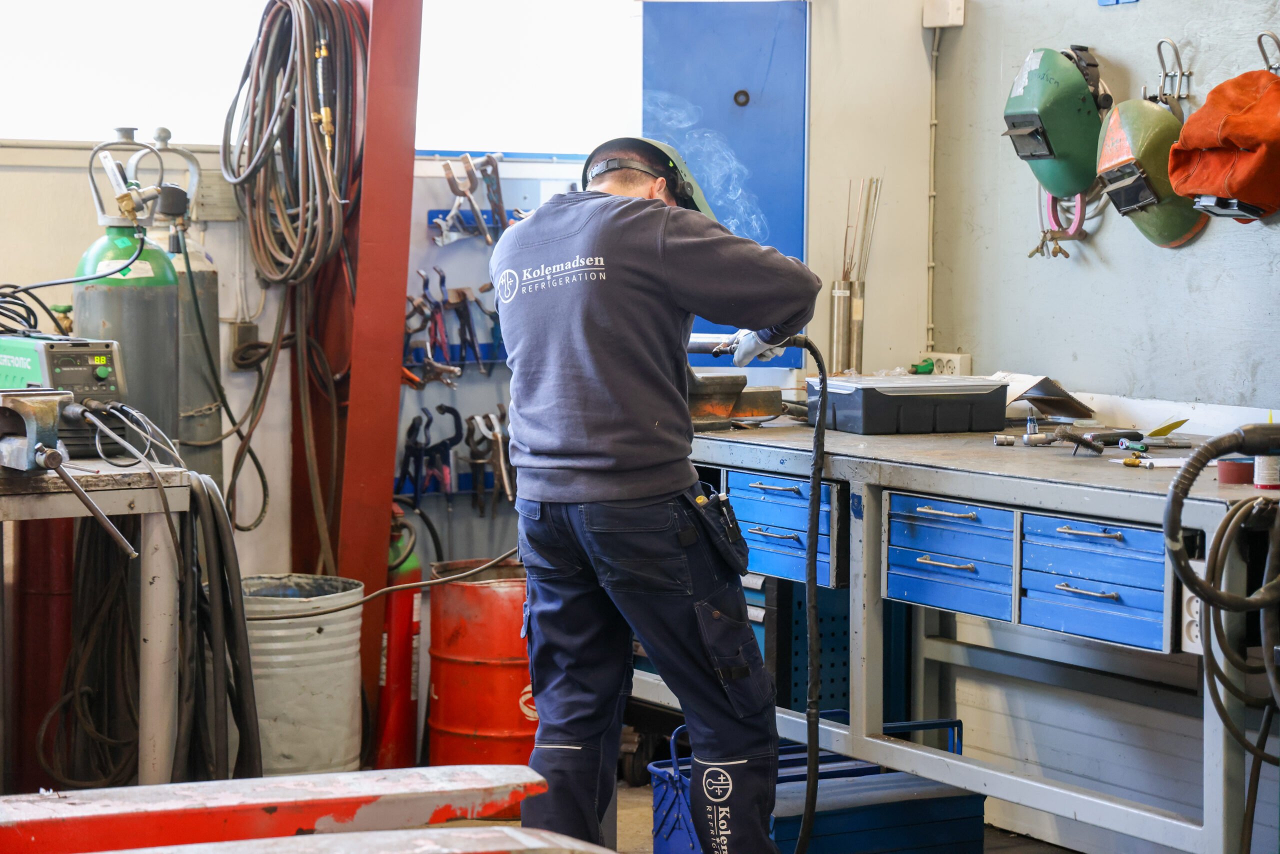 Mand svejser i værksted med værktøj og udstyr