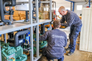 Teknikere installerer industrielt køleanlæg i værksted